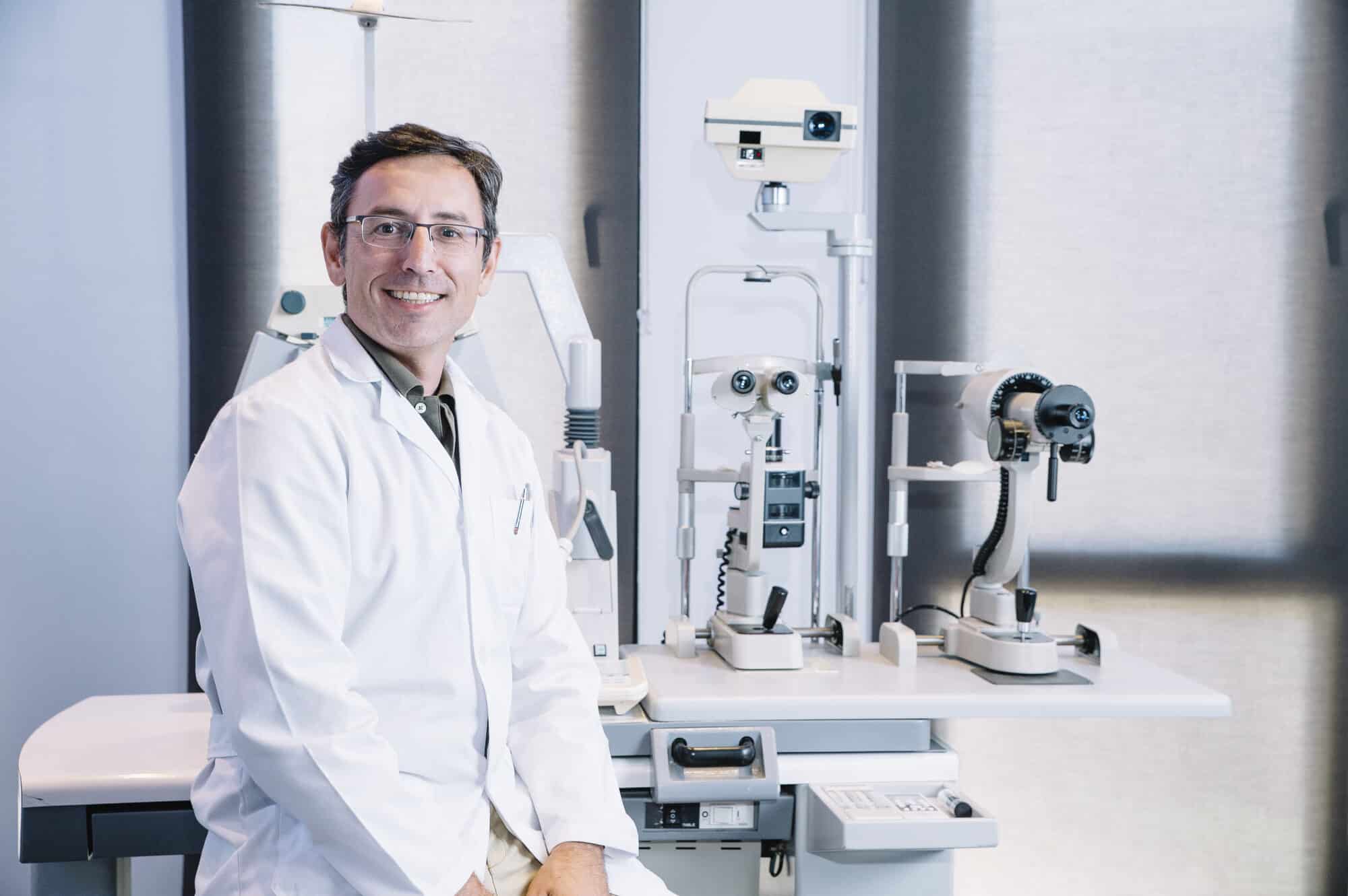 An ophthalmologist in a clinic exam room beside a slit lamp